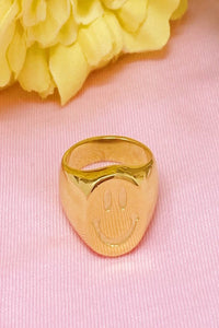 gold plated smiley face ring shown with yellow flower 
