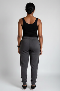Person wearing gray sweatpants and a black tank top on a plain background