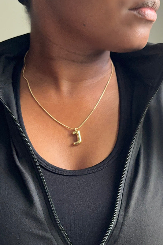 Person wearing a gold necklace with a pendant