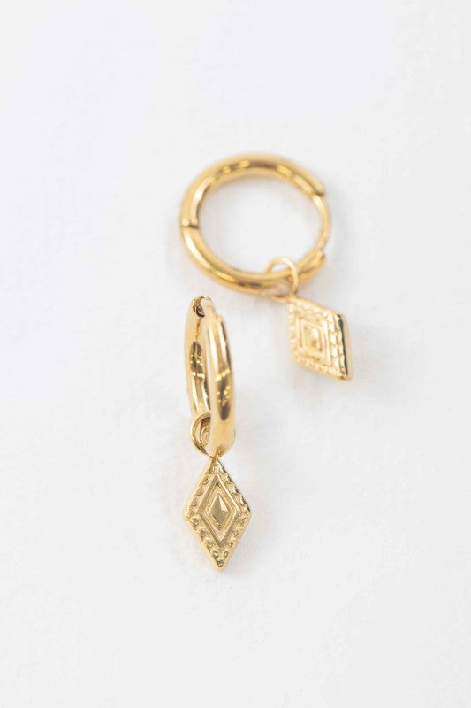 Close up of Dainty Gold dangle huggie hoop earrings on a whitebackground