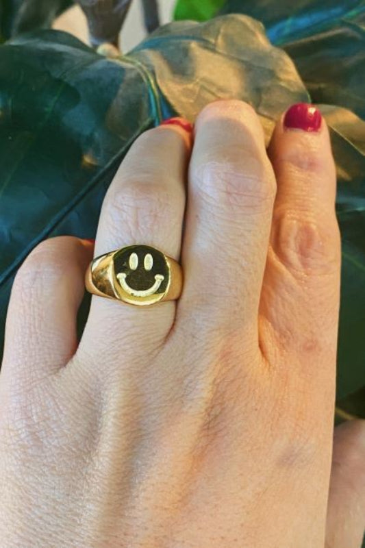 Close-up of gold smiley face signet ring with engraved happy face 