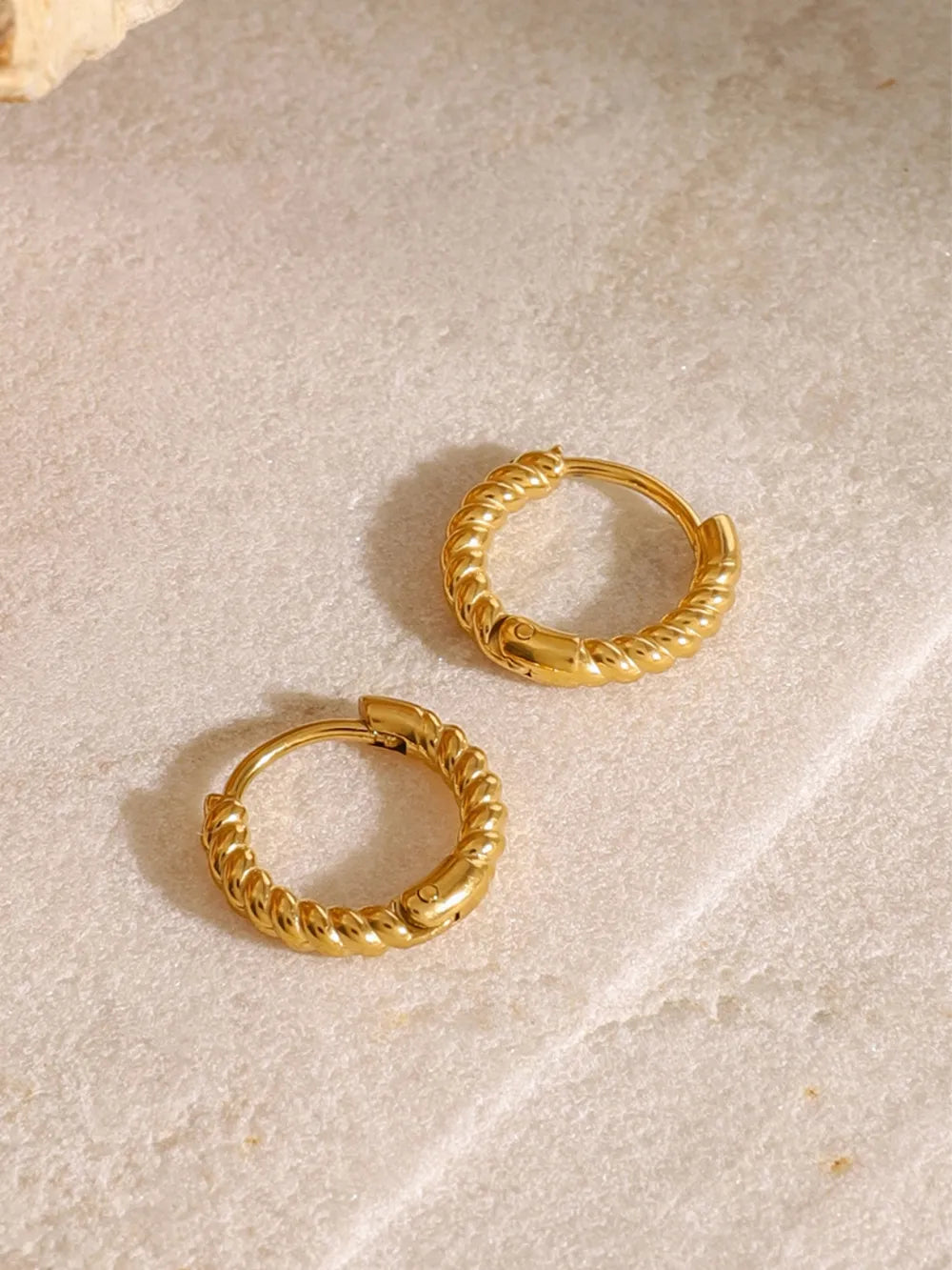 Close-up of twisted 18K gold-plated waterproof huggie earrings